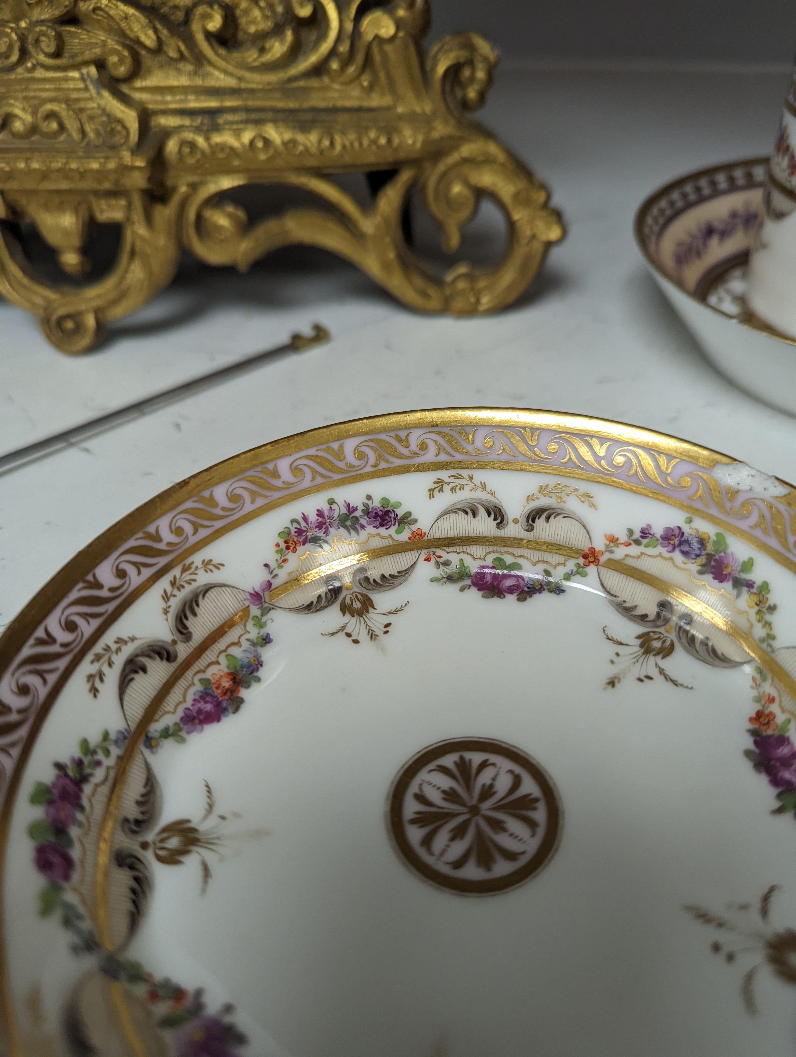 A Duc d'Angouleme coffee can and saucer painted with a puce chain of leaves on a salmon coloured ground and another painted with a flower chain, black feather and a gilt line, latter with stencilled red mark 'Manuf de M